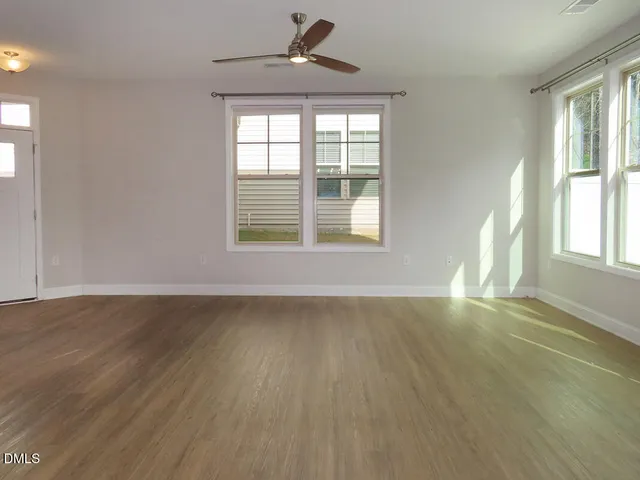 an empty room with wooden floor chandelier and windows