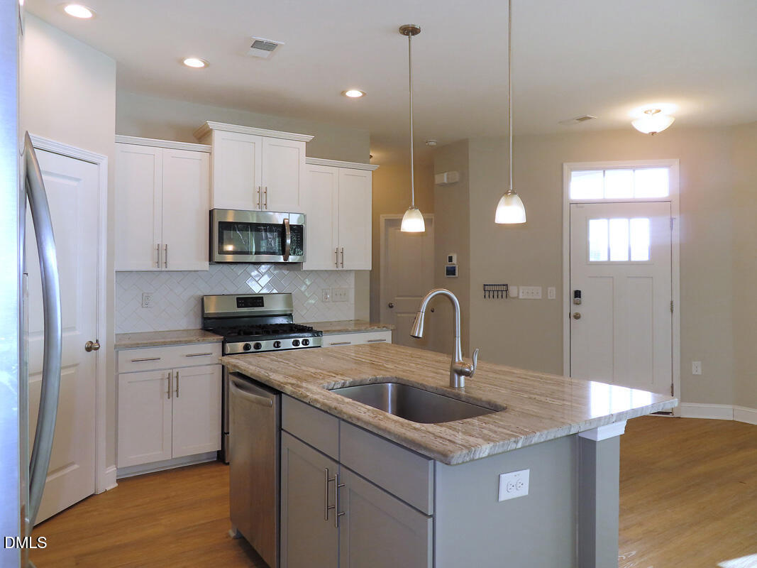 1217 Compass Drive Durham, NC 27713 - Photo 9 of 29 a kitchen with kitchen island a sink appliances and a counter top space