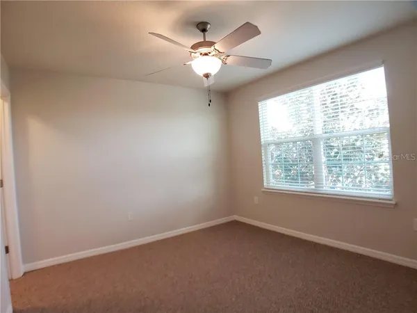 an empty room with a window and a fan