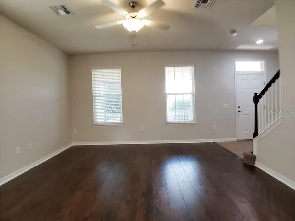 a view of an empty room with wooden floor and a window