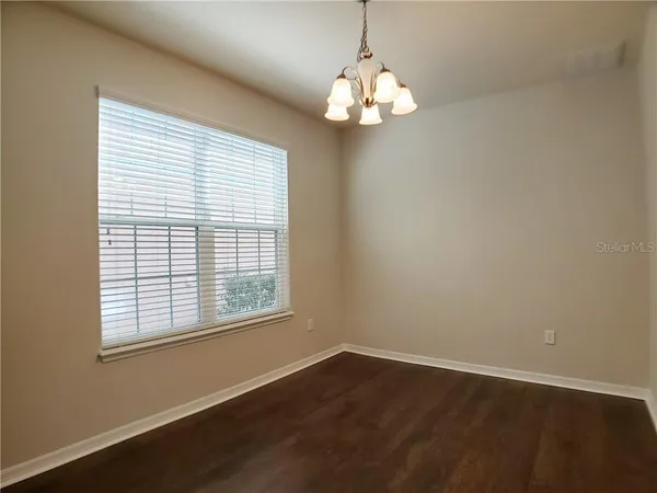 a view of a livingroom with a chandelier wooden floor and windows