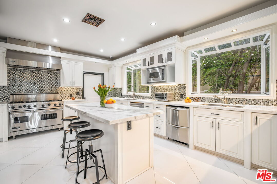607 North Hillcrest Road Beverly Hills, CA 90210 - Photo 7 of 16 a kitchen with white cabinets and white appliances