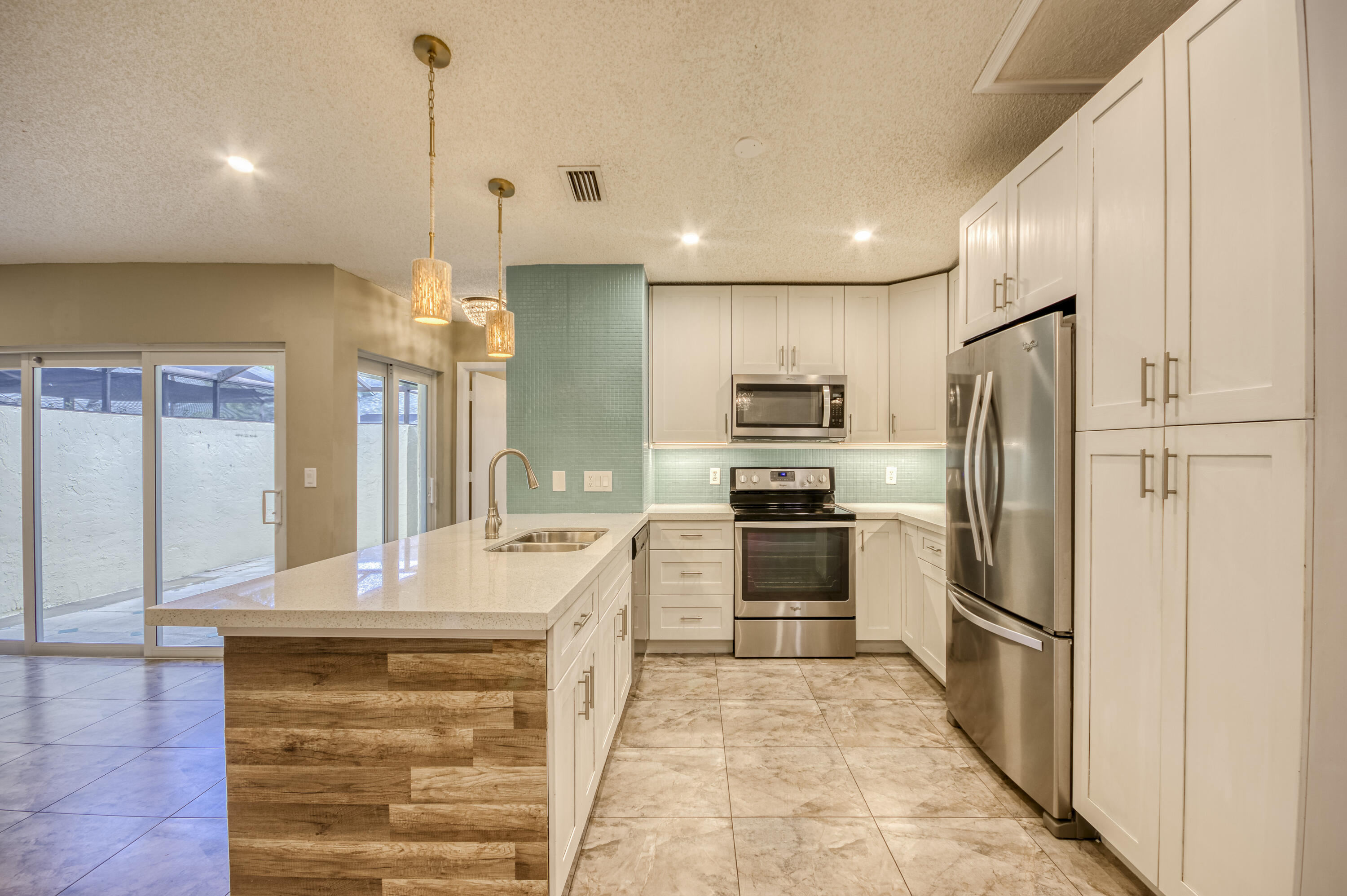 9109 Southwest 21st Street, Unit E Boca Raton, FL 33428 - Photo 9 of 24 a kitchen with granite countertop a refrigerator and a stove top oven