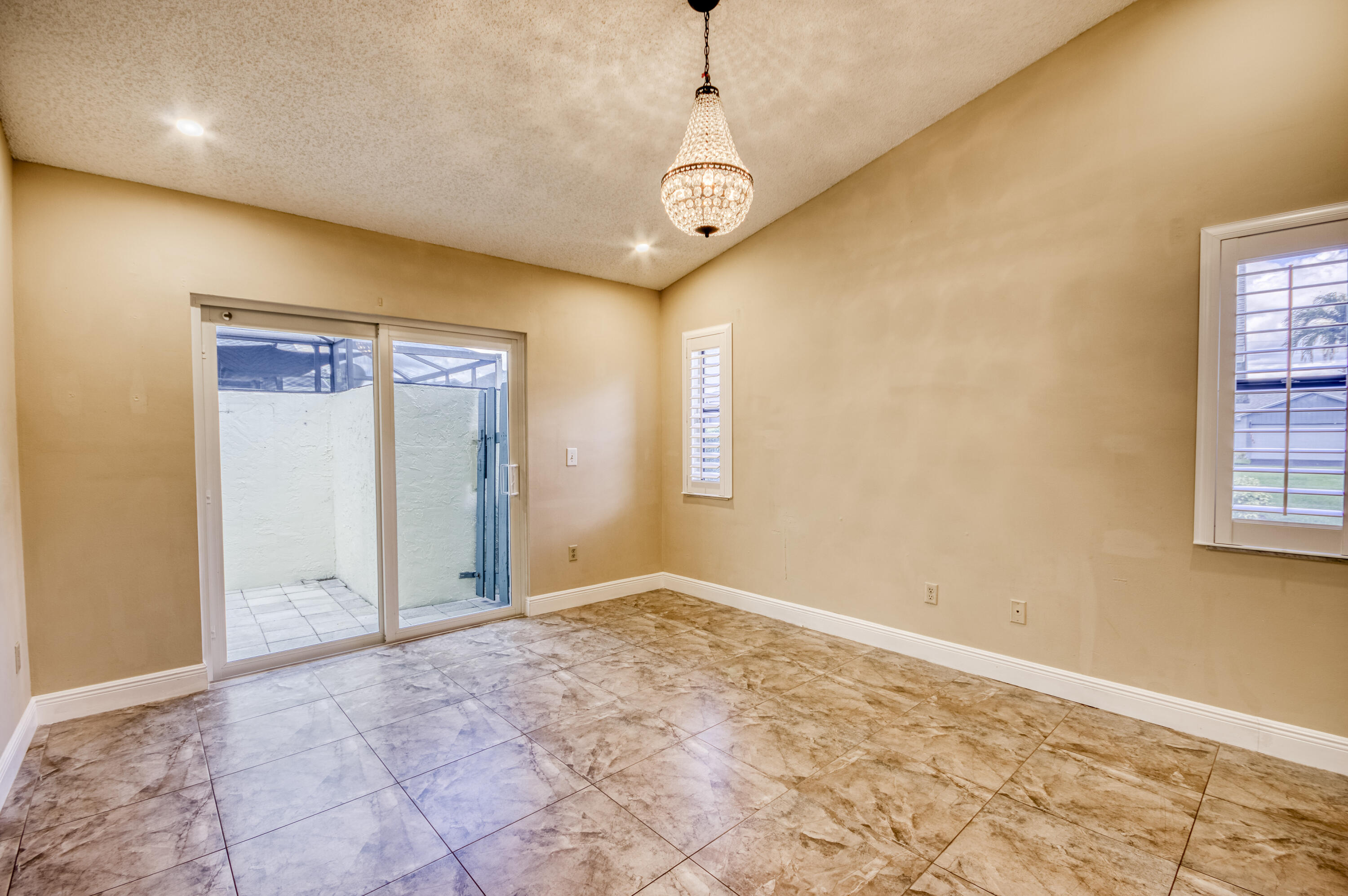 9109 Southwest 21st Street, Unit E Boca Raton, FL 33428 - Photo 10 of 24 a view of an empty room with window and chandelier fan