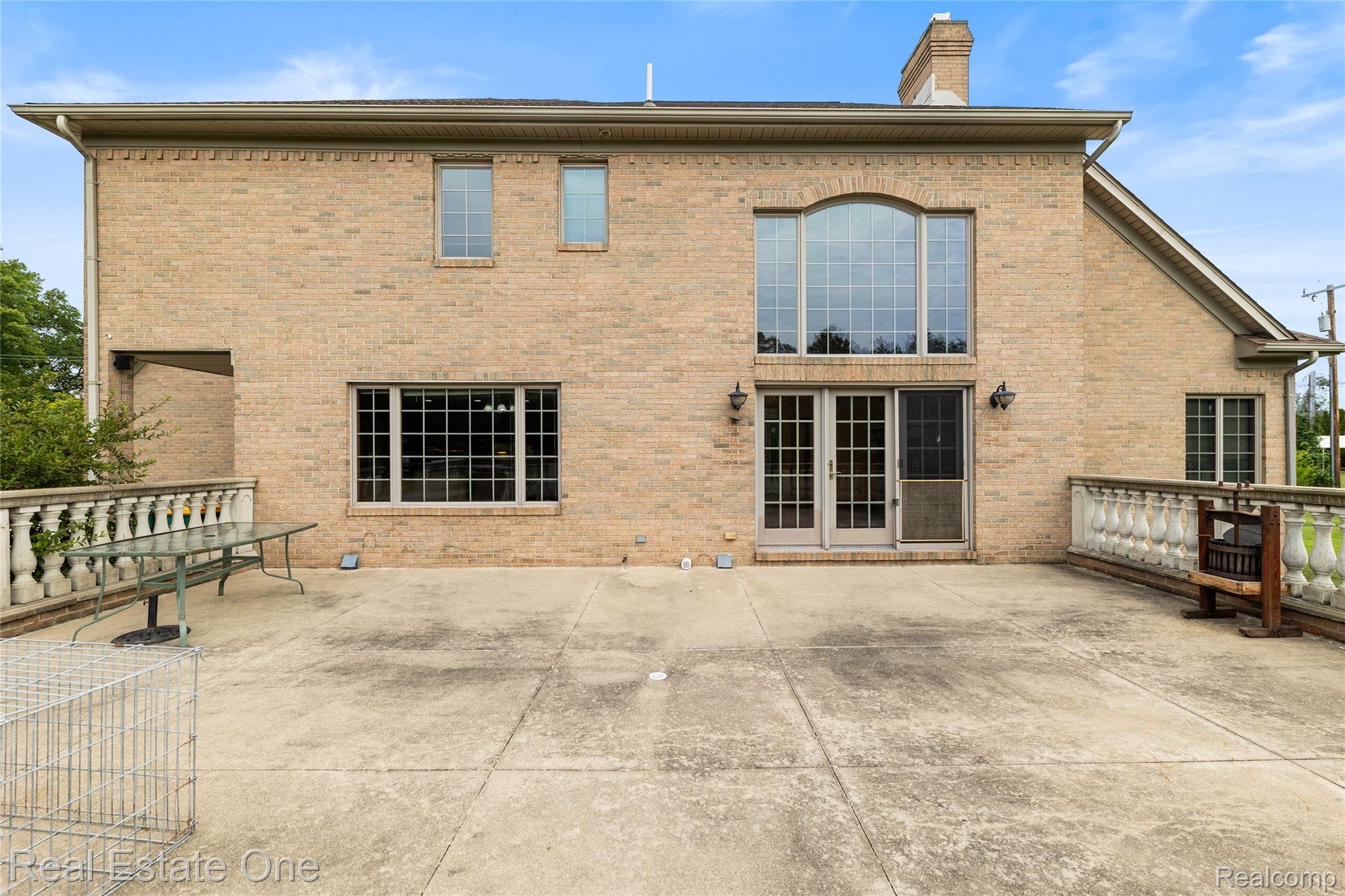 17268 Beech Daly Road Romulus, MI 48174 - Photo 21 of 60 Brick exterior featuring an arched window, multiple large windows, French doors, and a concrete patio with balustrade railings
