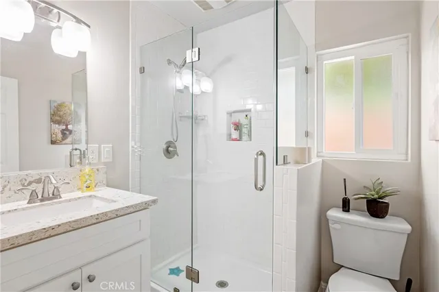 a bathroom with a granite countertop sink a toilet and shower