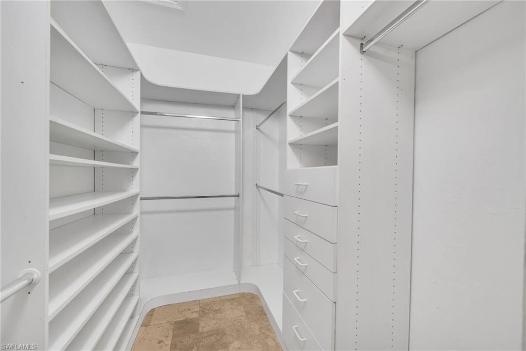 181 Napa Ridge Road East, Unit 35 Naples, FL 34119 - Photo 11 of 21 Custom walk-in closet featuring white built-in shelving, multiple hanging rods, and integrated drawers with white pulls