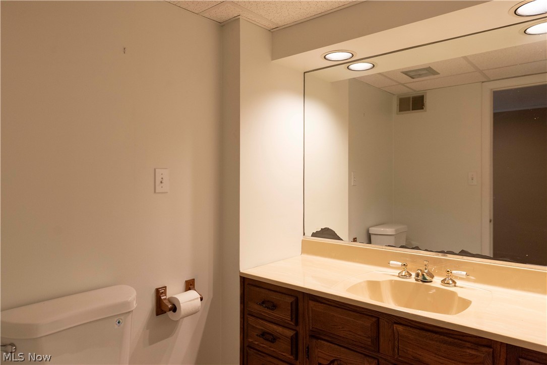 400 Baldwin Road Akron, OH 44312 - Photo 25 of 43 Convenient half bath in basement featuring a vanity with a light-colored countertop, an integrated sink, and an expansive mirror