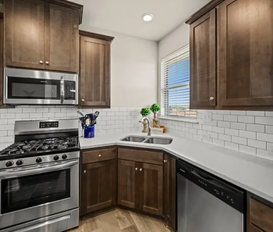a kitchen with stainless steel appliances a sink stove and microwave