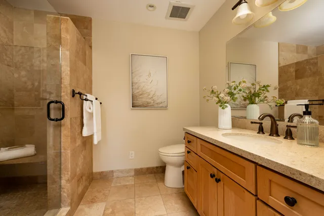 a bathroom with a granite countertop sink mirror vanity and toilet