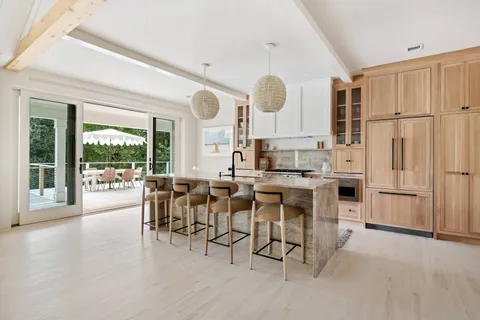 a kitchen with stainless steel appliances kitchen island granite countertop a table chairs and a view of living room