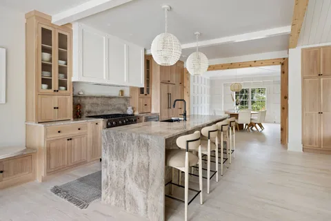 a very nice looking kitchen with granite countertop a stove a oven a dining table and chairs