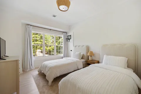 a bedroom with two beds and a large window