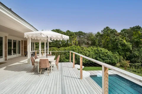 a balcony with wooden floor table and chairs