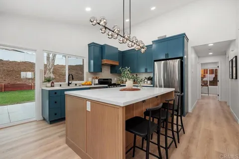 a kitchen with kitchen island a refrigerator a stove a sink dishwasher with a dining table and chairs