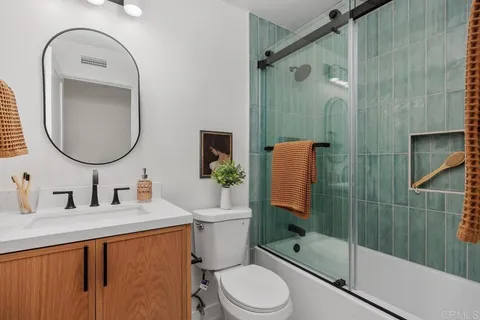 a bathroom with a granite countertop toilet sink shower and mirror