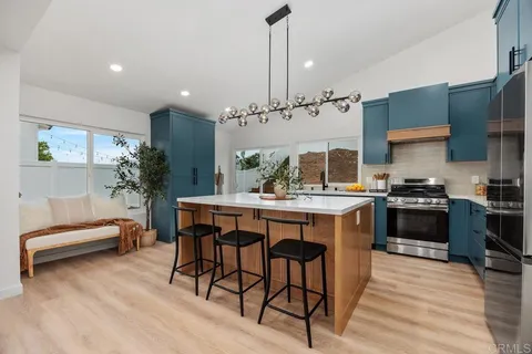 a kitchen with kitchen island a stove a table and chairs in it