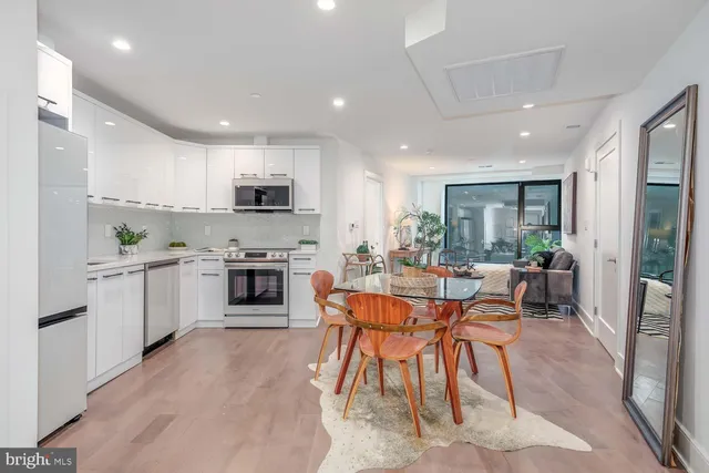 a kitchen with stainless steel appliances a stove a sink a refrigerator a dining table and chairs