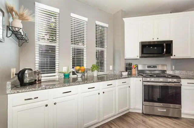 a kitchen with stainless steel appliances white cabinets a sink and a stove