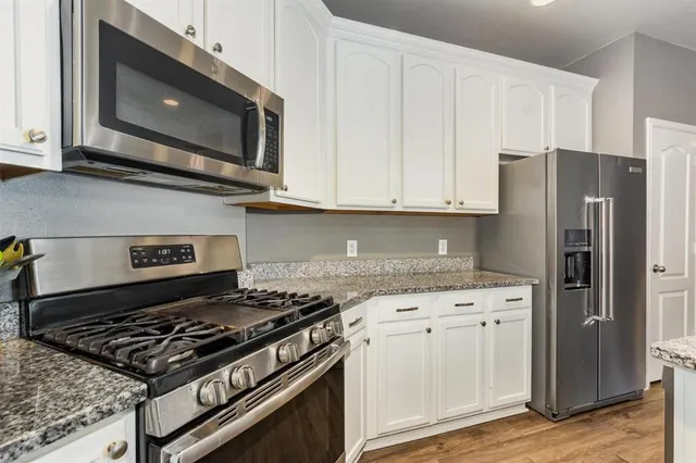 a kitchen with stainless steel appliances granite countertop a stove and a microwave
