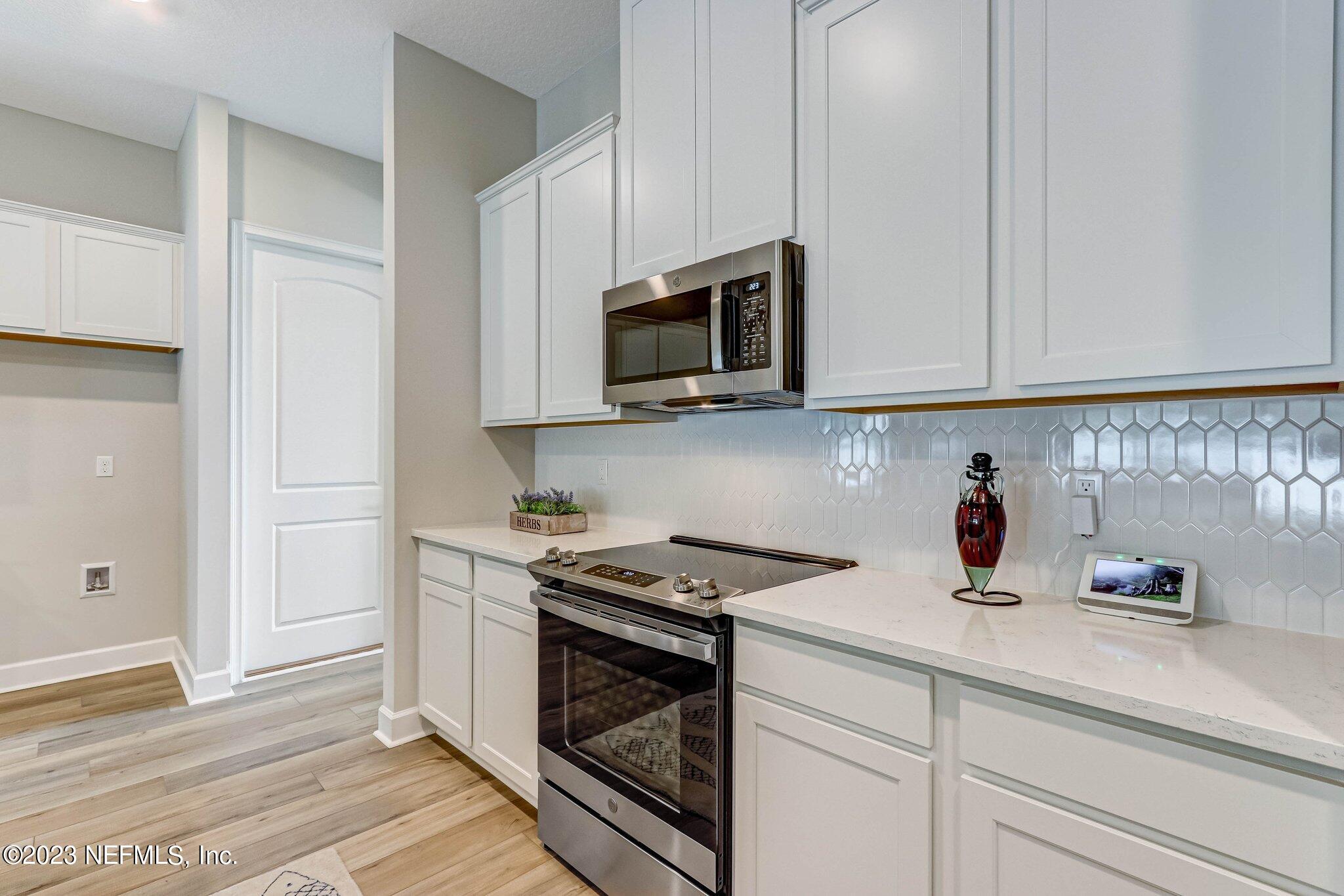 85156 Sandy Ridge Loop, Unit 18 Yulee, FL 32097 - Photo 11 of 25 a kitchen with stainless steel appliances granite countertop white cabinets and a stove top oven