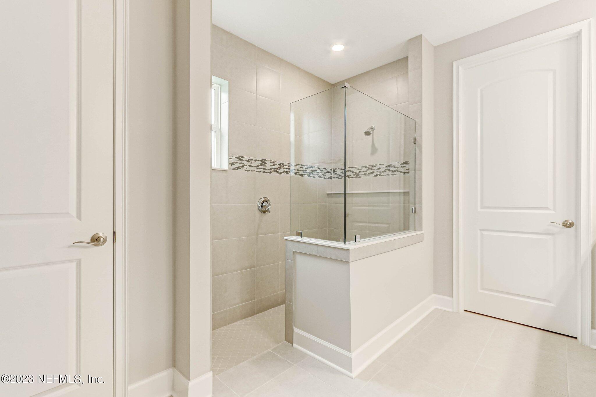 85156 Sandy Ridge Loop, Unit 18 Yulee, FL 32097 - Photo 18 of 25 a bathroom with a glass shower door and a mirror