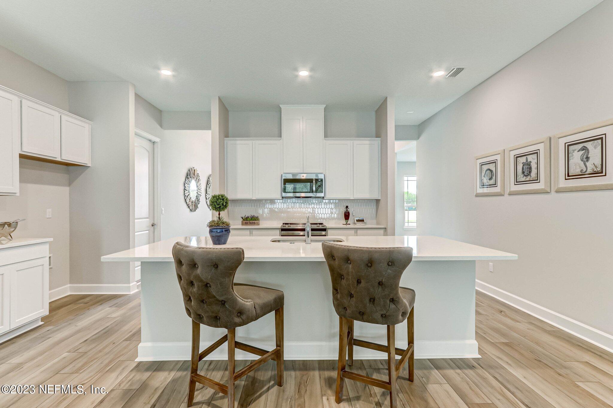 85156 Sandy Ridge Loop, Unit 18 Yulee, FL 32097 - Photo 9 of 25 a kitchen with stainless steel appliances kitchen island granite countertop a dining table chairs and a refrigerator a sink