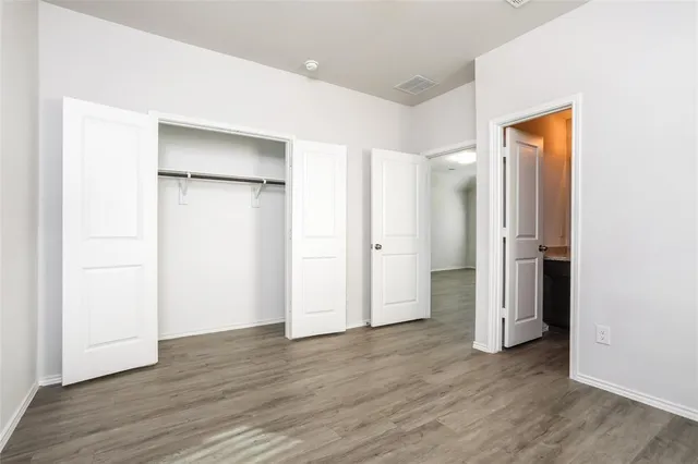 an empty room with wooden floor & closet area