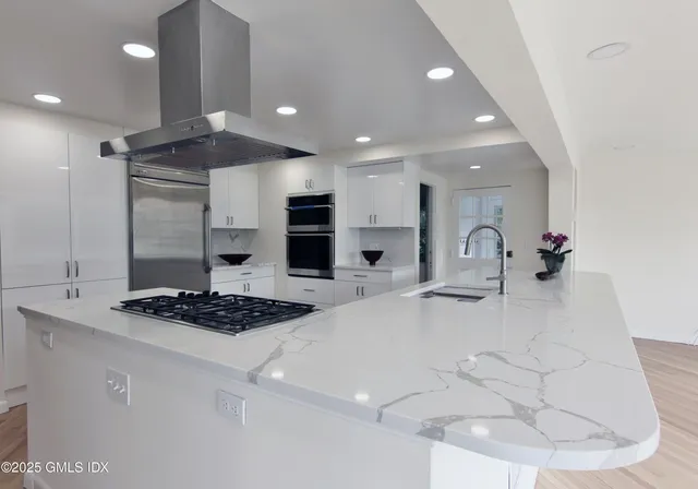 a kitchen with stainless steel appliances kitchen island granite countertop a sink a stove and a refrigerator