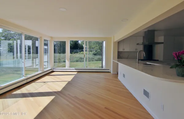 a large white kitchen with wooden floor and a large window