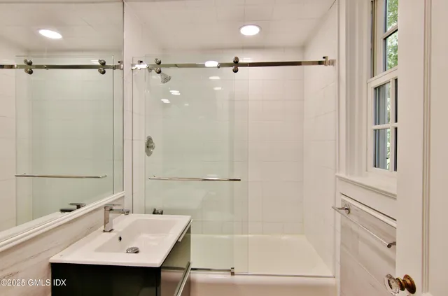 a bathroom with a sink shower and a mirror