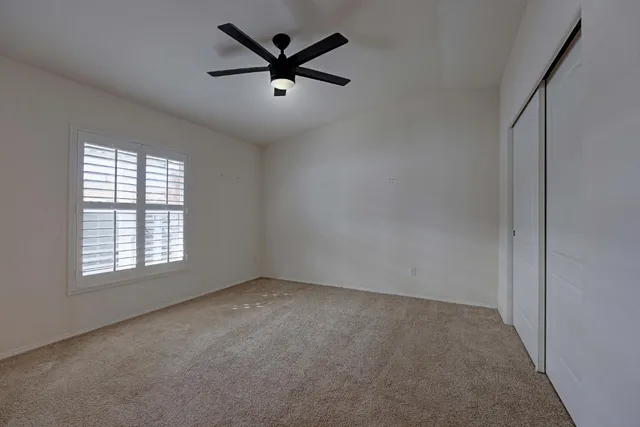 an empty room with a window and a fan