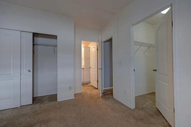 a view of an empty room with closet and a bathroom