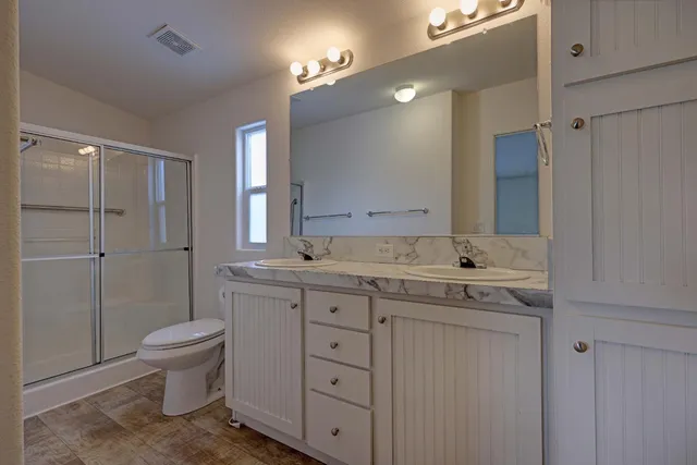 a bathroom with a double vanity sink toilet and shower