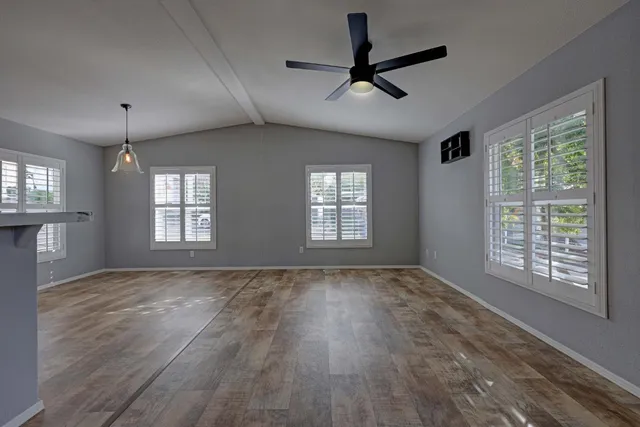 a view of an empty room with a window and wooden floor