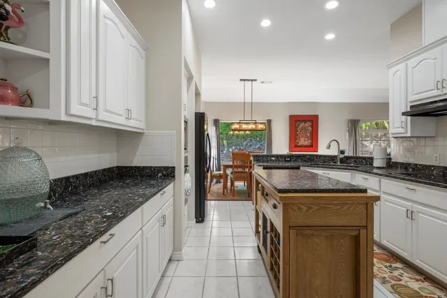 a living room with stainless steel appliances kitchen island a table and chairs in it