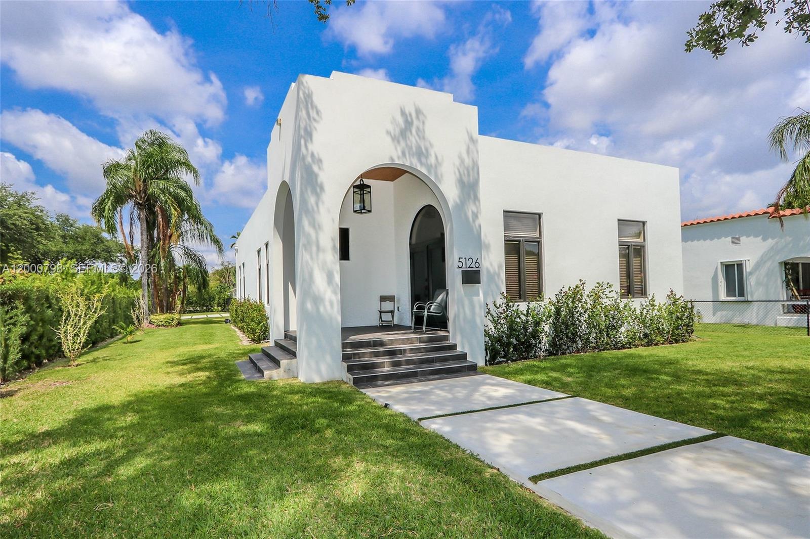 5126 Southwest 57th Avenue Miami, FL 33155 - Photo 2 of 32 a view of a white house with a small yard plants and a large tree