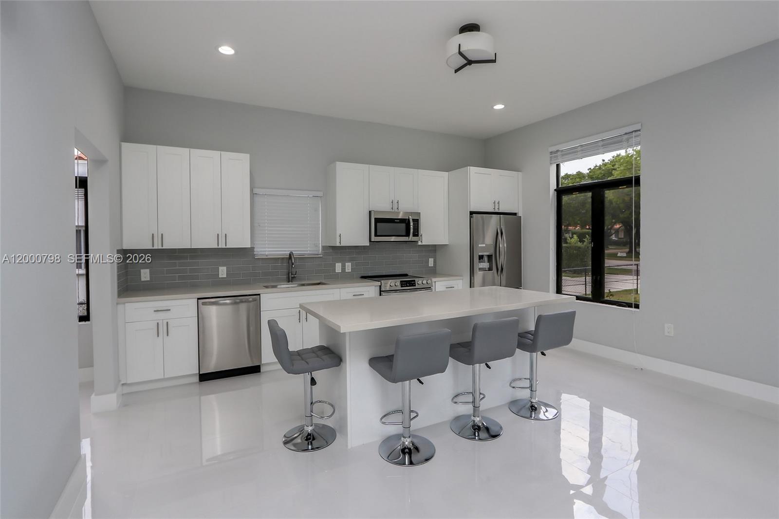 5126 Southwest 57th Avenue Miami, FL 33155 - Photo 5 of 32 a kitchen with stainless steel appliances granite countertop a sink a stove a refrigerator cabinets and chairs