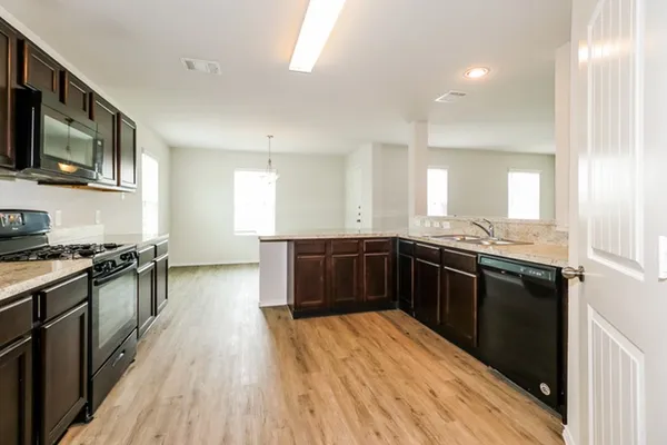 a kitchen with stainless steel appliances granite countertop a stove and a wooden floors