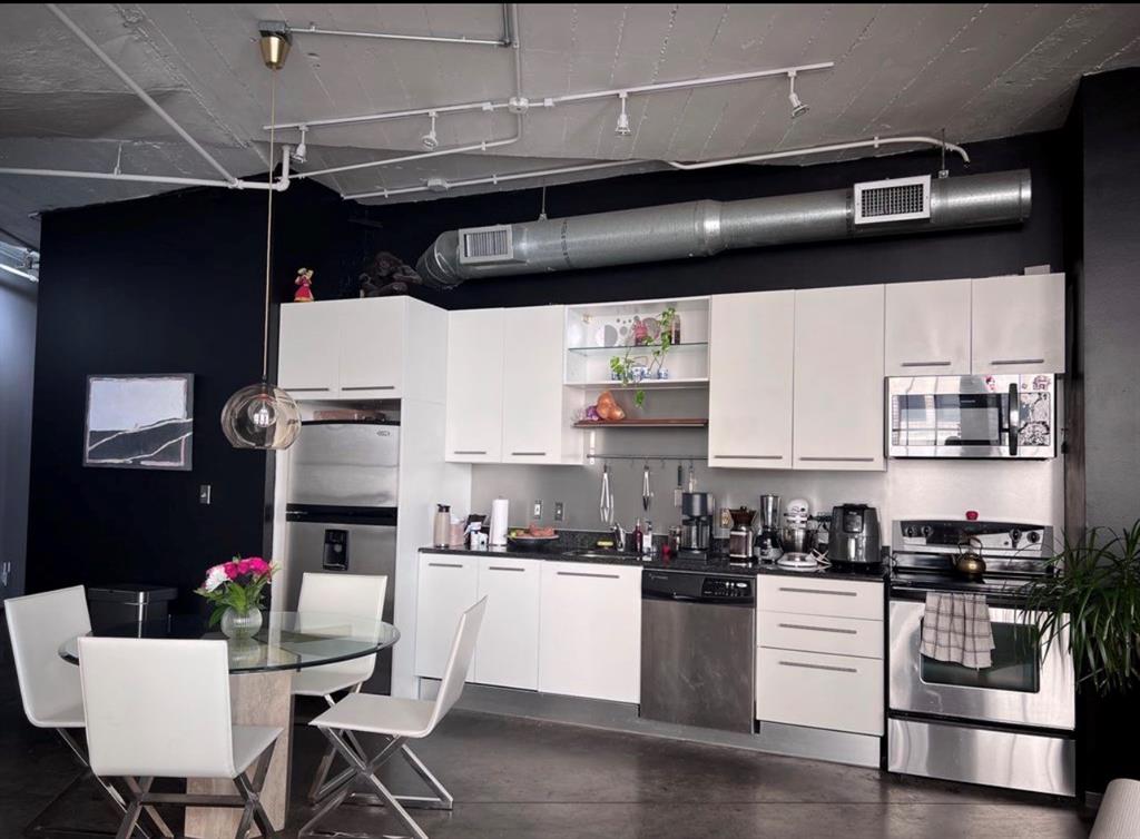 1122 Jackson Street, Unit 514 Dallas, TX 75202 - Photo 21 of 40 Modern kitchen featuring white cabinetry, stainless steel appliances, dark countertops, and exposed industrial-style ductwork