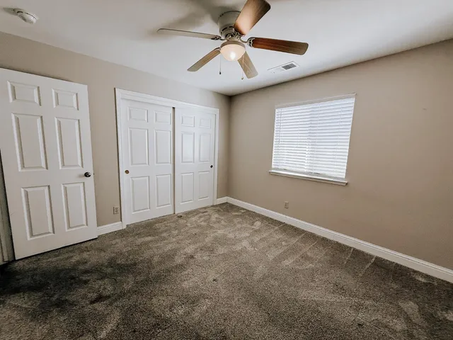 an empty room with windows and fan