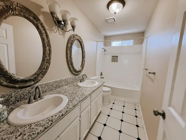 a bathroom with a granite countertop sink mirror vanity and toilet
