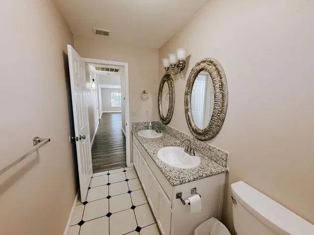 a bathroom with a granite countertop sink mirror vanity and toilet