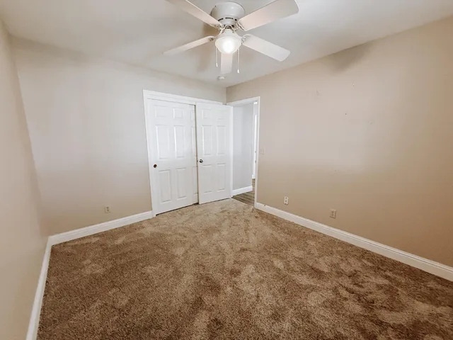 an empty room with a chandelier fan and windows