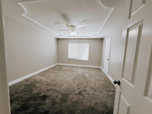 an empty room with windows and chandelier fan
