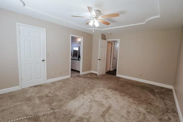 an empty room with closet and a ceiling fan