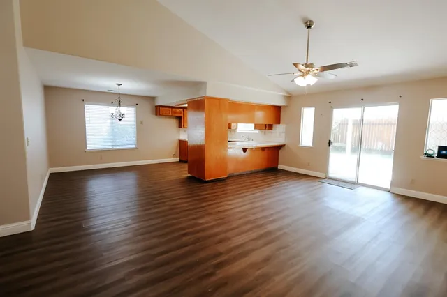 a view of a room with wooden floor a ceiling fan and windows