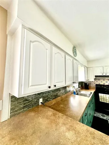 a kitchen with granite countertop a sink a stove and cabinets