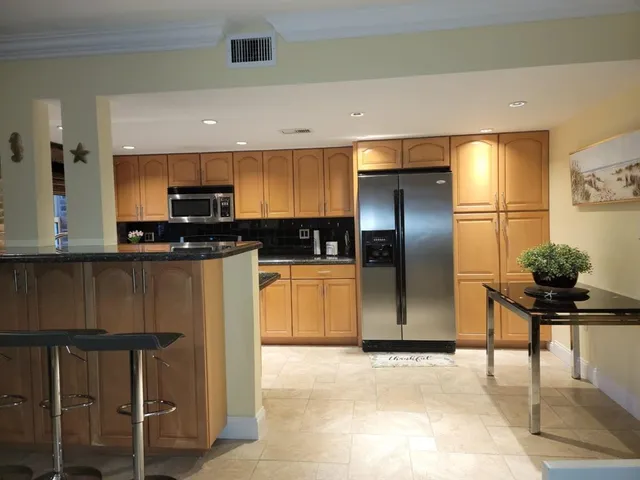 a kitchen with stainless steel appliances kitchen island granite countertop a refrigerator and a stove top oven
