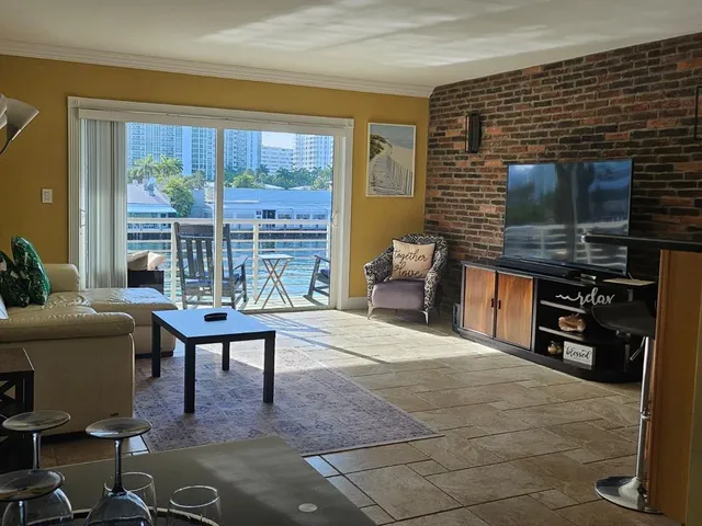a living room with furniture a flat screen tv and a floor to ceiling window